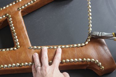 While holding trim in place with one hand, other end of trim going down the inside side of the 'leg' of letter "A" is being cut.