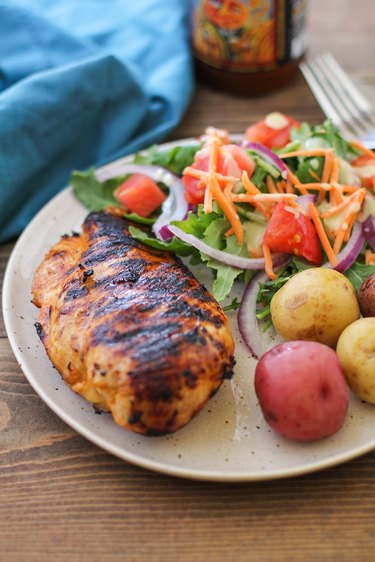 Grilled chicken on a plate with potatoes and salad