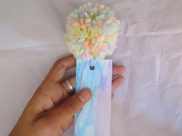 Looping the yarn pompom tail through the hole punch