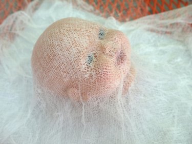 Doll face covered in cheesecloth and starch.