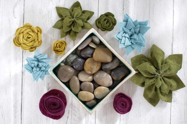 Container filled with river rocks and surrounded by DIY felt succulent plants