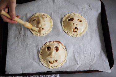 Brushing shrunken head pies with egg wash