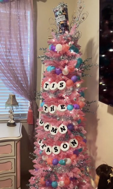 Pink Christmas tree with a garland reading "Tis The Damn Season"