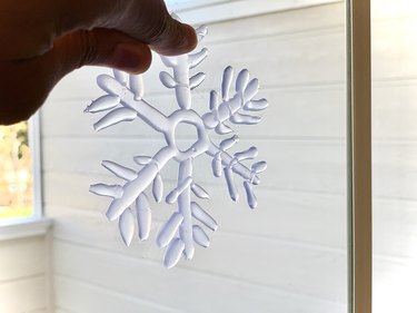 pressing hot glue snowflake onto window