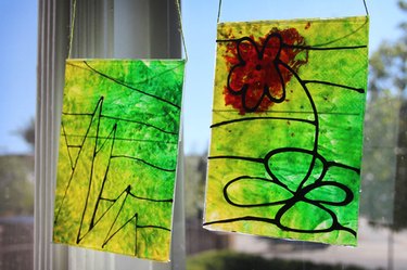 Two yellow and green melted crayon sun catchers hanging in a sunny window