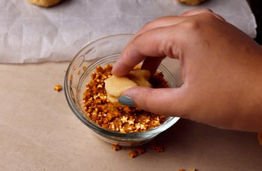 Rolling sugar cookie dough in a small bowl of star sprinkles