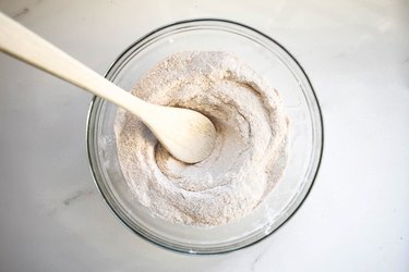 Making a well in the center of the dry ingredients with a wooden spoon.