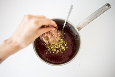 Sprinkling pistachios into the mixture.