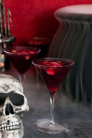 Close up of a class of sangria with smoking cauldron behind it
