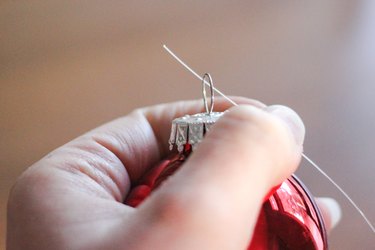 Threading fishing line through Christmas ornaments.