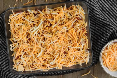 Topping a Cheeseburger Casserole Recipe with shredded cheddar cheese