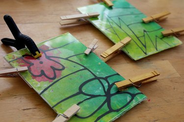 Acrylic and melted crayon art clamped together while drying