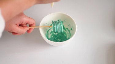 drizzling white chocolate over marshmallow pops