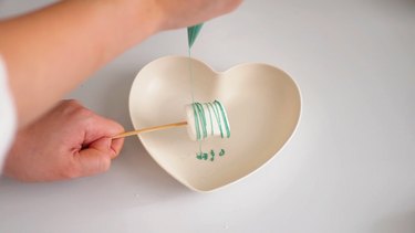 drizzling green-colored chocolate over marshmallow pops
