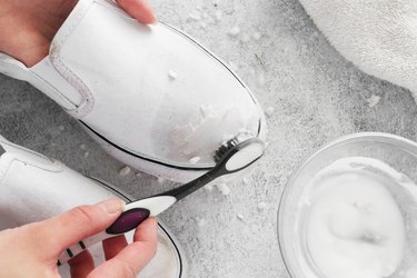 Scrubbing paste onto white canvas shoes