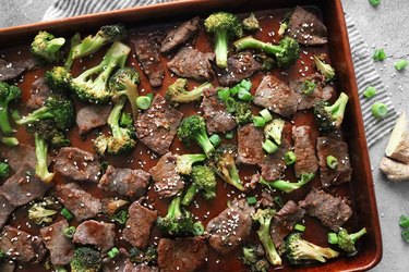 Sheet pan beef and broccoli garnished with sesame seeds and scallions
