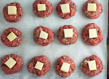 Raw meatballs with a cube of cheese pressed into the top of each.
