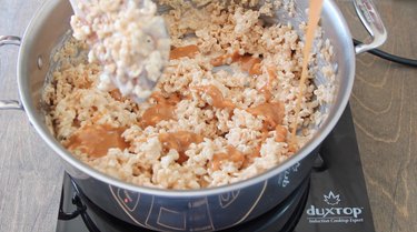 Stirring caramel into Krispies mixture.