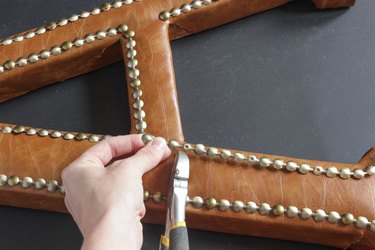 Point of nailhead trim where nail is driven is is lined up with corner of inside 'leg' of letter "A".