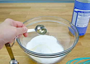 Adding Castile soap to a bowl for toilet cleaning tablets