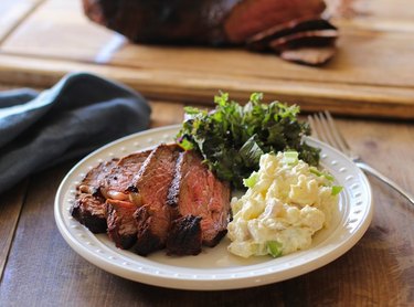 tri-tip, potato salad, and kale salad on a plate