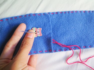 Sewing an owl button onto the DIY felt pencil case