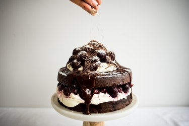 Hand sprinkling chocolate shavings over the decorated cake.