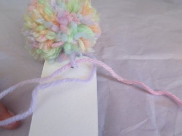 Knotting the tail of yarn for a pompom bookmark