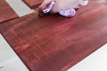 Staining pine wood with plastic gloves for protection.