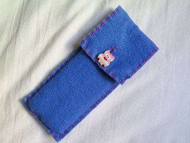 The button pulled through the embroidered slit on the DIY felt pencil case
