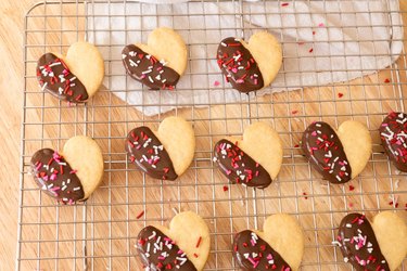 Heart-shaped shortbread cookies dipped in chocolate, arranged on a wire rack.