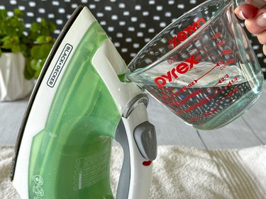 Pour vinegar-water mixture into iron