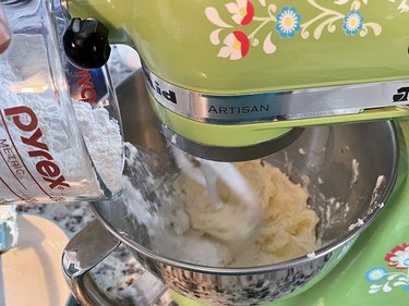 Clear cup of flour being poured into lime green stand mixer