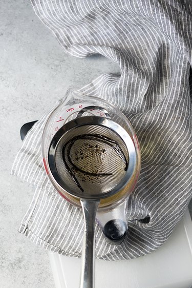 Fine mesh strainer in a measuring cup, straining vanilla simple syrup