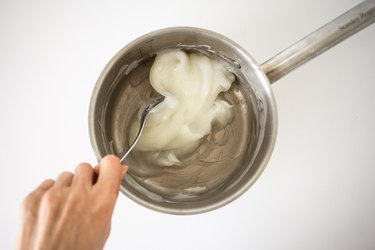Hand stirring the thickening paste in a saucepan.