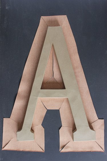 Letter "A" monogram sitting on top of fabric, cut out around it with slits cut in at corners.
