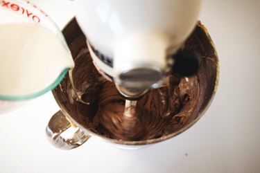 Buttermilk poured from a liquid measuring cup into the mixer.