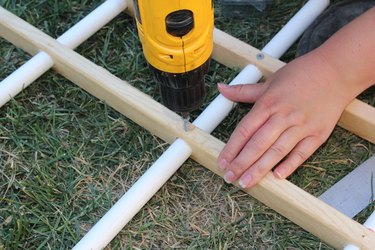 Securing the PVC into the wood with a screw.
