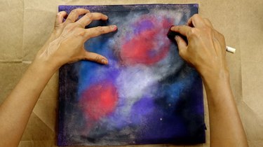 Sponging fabric paint onto cushion cover in circular motion.