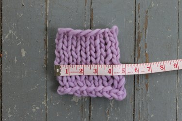 Using measuring tape to measure the gauge swatch.
