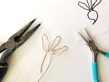 An image of textured and folded brass wire, pliers, and a drawing of a beet.