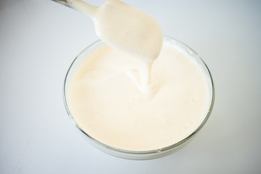 Spatula testing batter thickness over a glass mixing bowl.