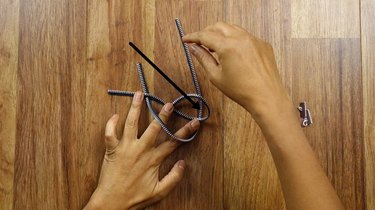 Tying a knot to make a knotted bracelet from a zipper.