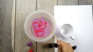 Mixing two nail polish colors for nail polish marbled mugs.