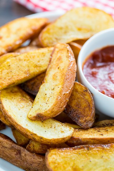 Pan fried potato wedges on a plate with ketchup