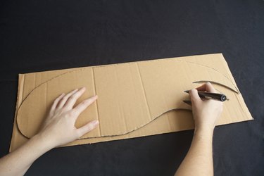 Cutting a wing shape from a sheet of cardboard.