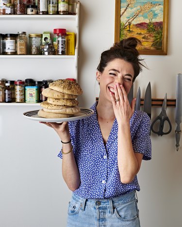 Woman holding up a plate of breads and laughing