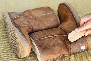 Someone brushing a pair of dark brown UGG boots