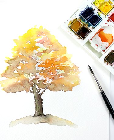 Finished watercolor painting of a fall tree next to a paint palette