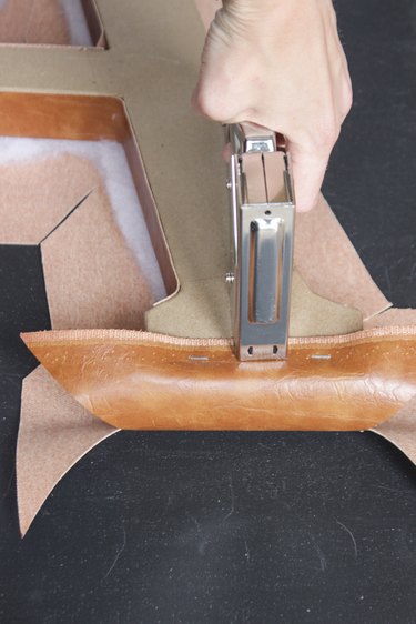Fabric being stapled down on bottom part of letter "A"